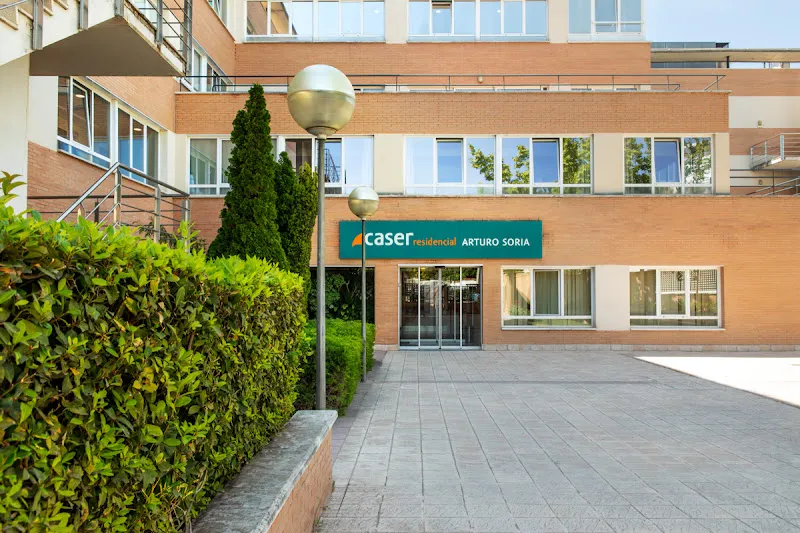 Fachada y entrada principal del caser residencial arturo soria con jardín y puerta de cristal.
