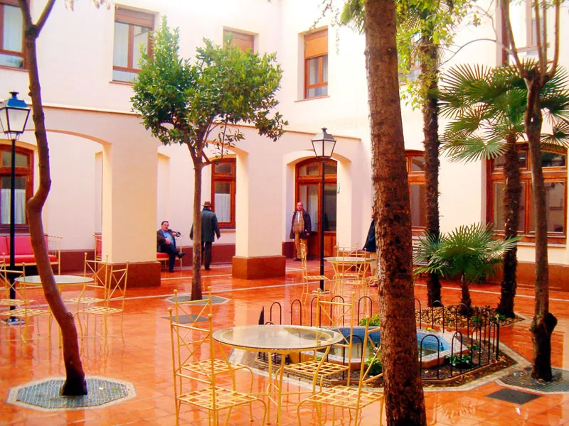 Patio interior con mesas, sillas y árboles en el centro geriatrico dos de mayo
