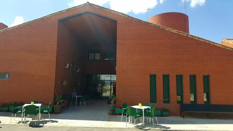 Fachada con porche y terraza con mesas y sillas verdes del centro residencial los llanos asociacion edad dorada mensajeros de la paz clm galicia