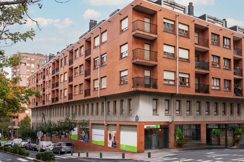 Fachada en esquina de la residencia domusvi arbidea con balcones y planta baja comercial