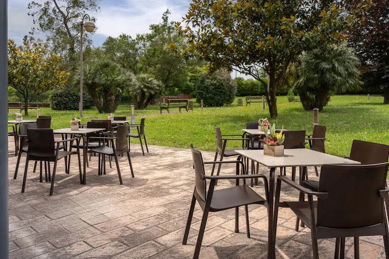 Terraza exterior ajardinada con mesas, sillas y macetas en domusvi berra.