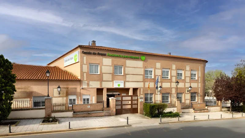 Fachada exterior de domusvi conde orgaz con entrada, banderas y jardín frontal