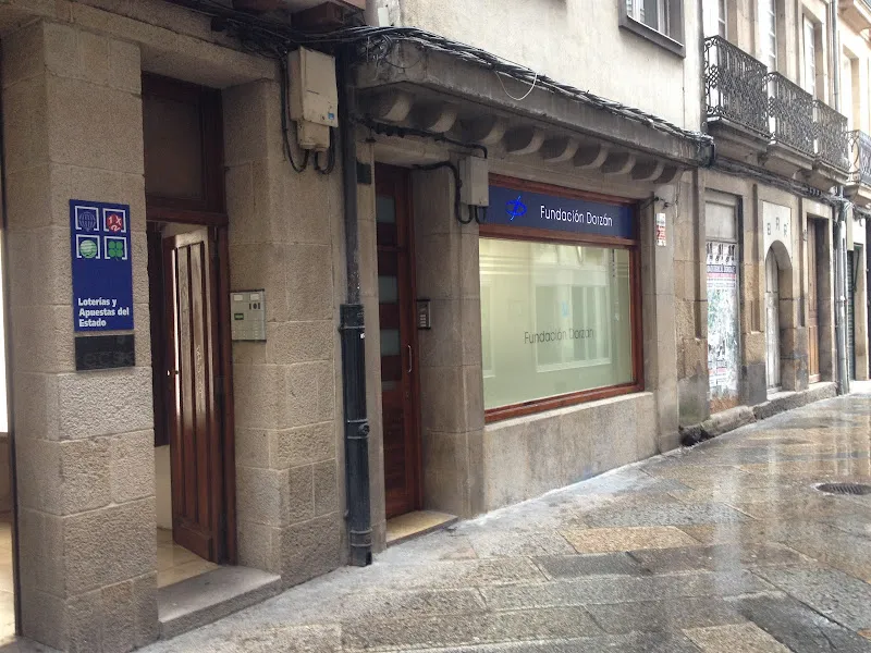 Fachada de la fundacion dorzan en edificio de piedra con escaparate y rótulo azul