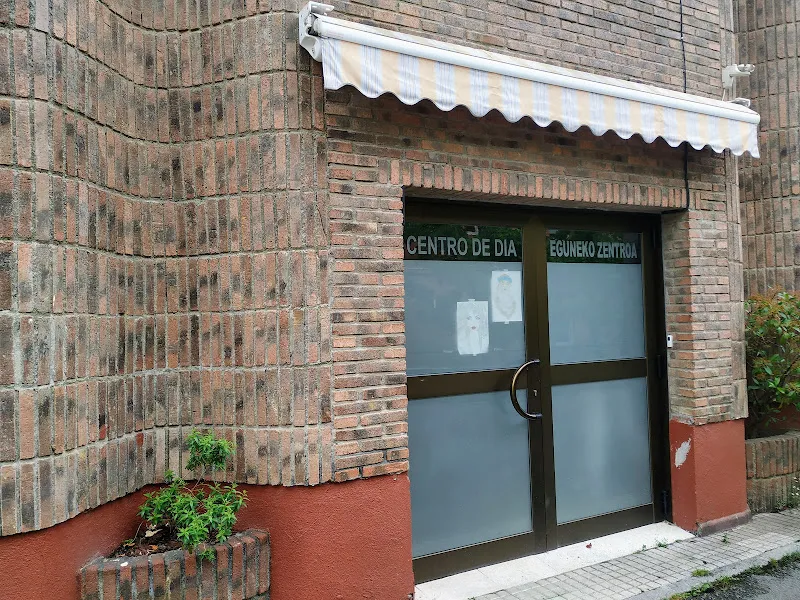 Fachada y entrada de centro de día en ladrillo - gsr legazpi santa cruz con puerta doble de vidrio, toldo rayado y macetero en la base