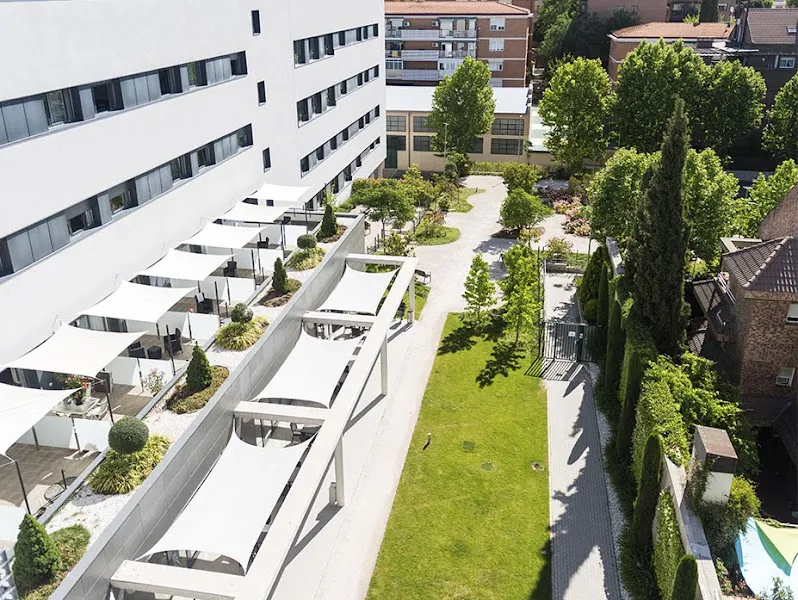 Edificio blanco con terrazas sombreadas, jardín y paseo exterior en mgs seniors madrid edalia
