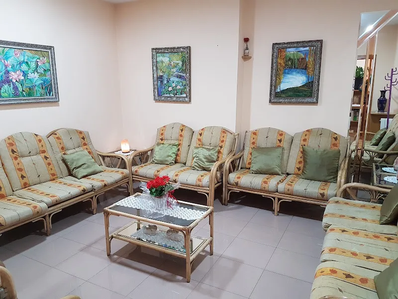 Sala común con sofás de mimbre, cojines verdes y mesa de centro en mio cid hogar residencial.