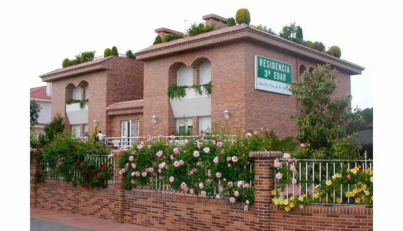 Fachada ajardinada de nuestra sra de la antigua residencia geriatrica con muros de ladrillo, balcones y rosales.