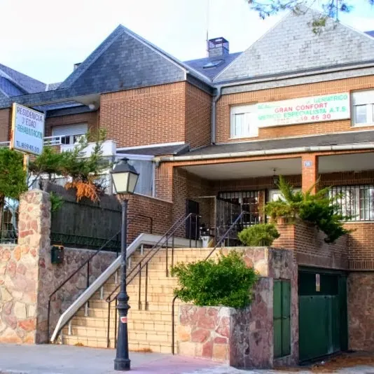 Entrada principal de la residencia de ancianos acacias torrelodones con escalera, barandilla y vegetación