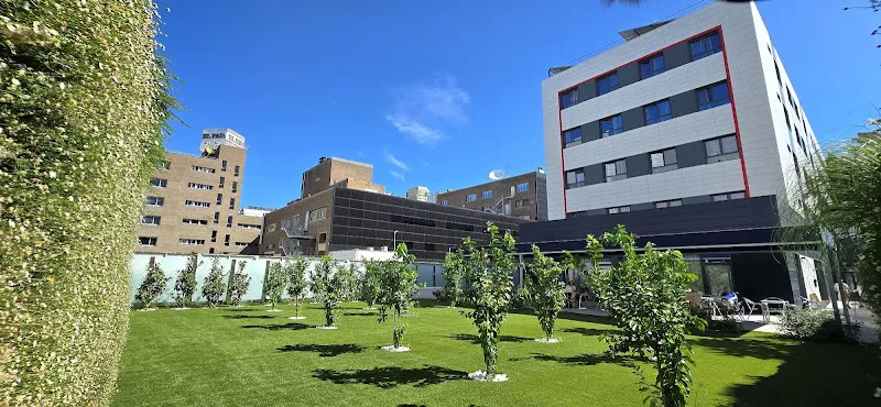 Fachada contemporánea y jardín con césped y árboles pequeños en residencia de ancianos simancas madrid vitalia home, con terrazas y áreas de ocio al aire libre