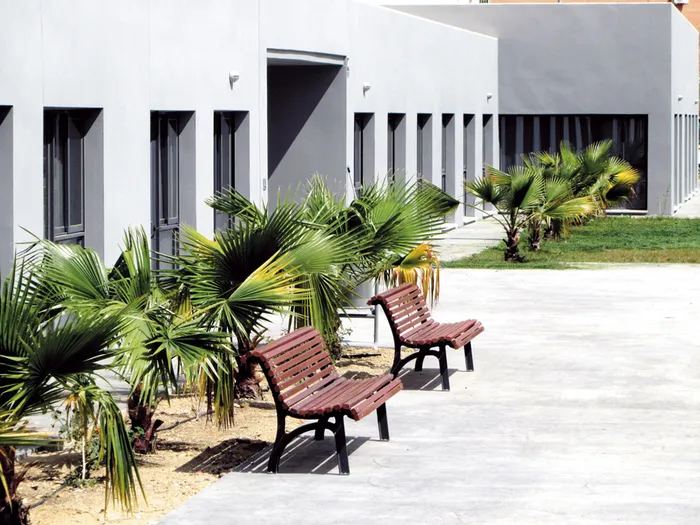 Patio exterior con bancos de madera y palmeras frente a la residencia de ancianos vitalia alcosa sevilla vitalia home.