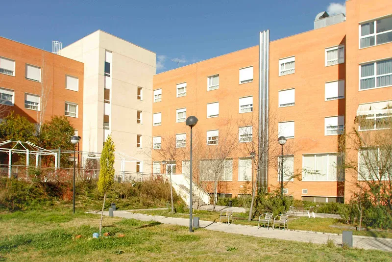 Fachada y jardín de la residencia de mayores amavir ciudad lineal con caminos, bancos y ventanas en un edificio de varios pisos