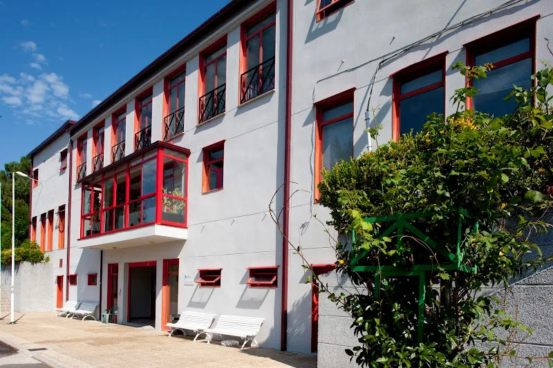 Edificio blanco con marcos rojos y bancos exteriores de la residencia de mayores bande
