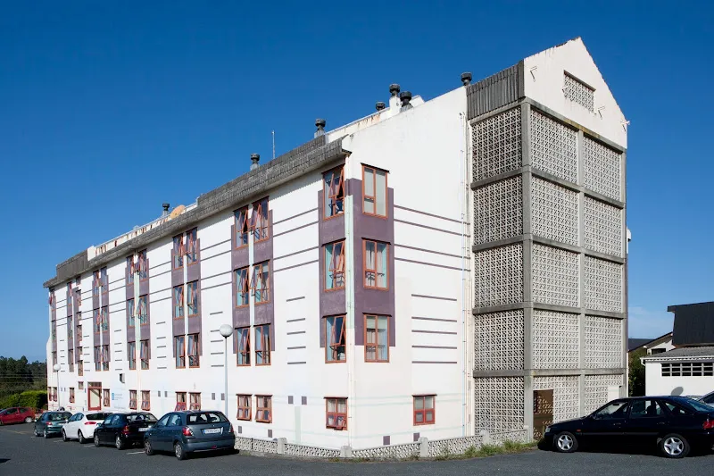 Edificio de varios pisos con numerosas ventanas y coches aparcados junto a la residencia de mayores laraxe