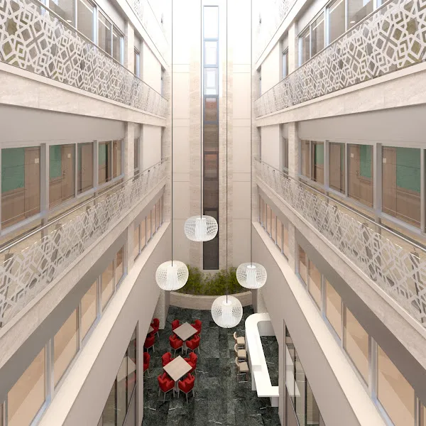 Atrio interior luminoso de la residencia de mayores sevilla macarena emera con mesas, sillas rojas, mostrador y lámparas colgantes