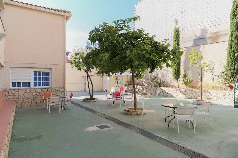 Patio exterior con mesas, sillas y árboles en la residencia de personas mayores anos dorados ii.