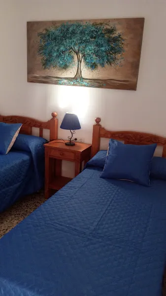 Habitación con dos camas individuales, lámpara y cuadro decorativo en residencia dona emilia