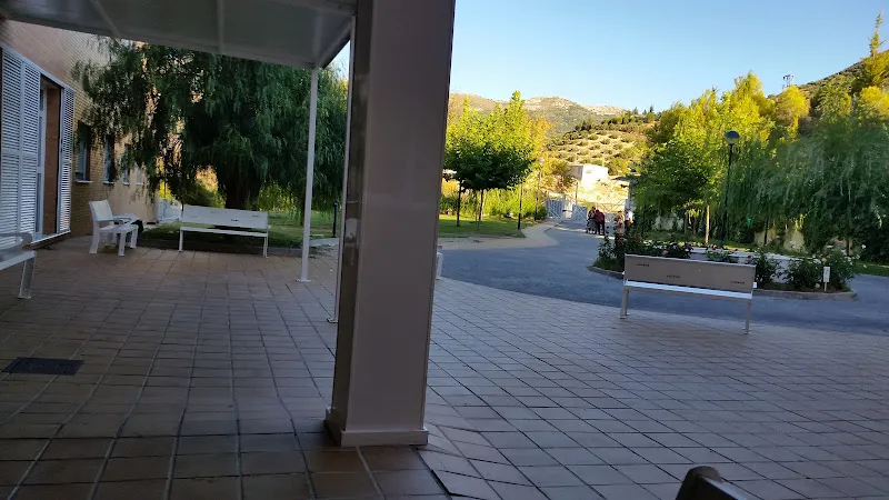 Patio con bancos y árboles en una residencia edades junto a jardines y vistas montañosas.