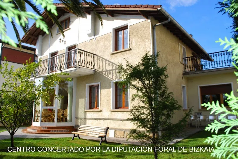 Fachada de la residencia elizalde con balcón, porche acristalado y jardín.