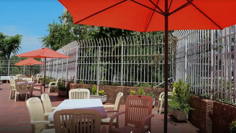 Terraza exterior con mesas, sillas y sombrillas en residencia geriatel aluche