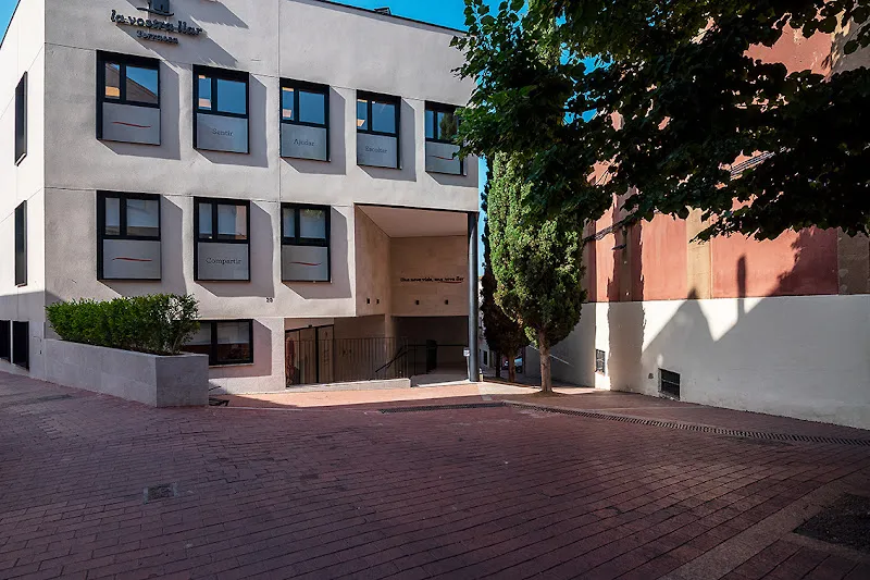Fachada moderna y acceso principal de la residencia geriatrica la vostra llar terrassa con rampa, ventanas y árboles