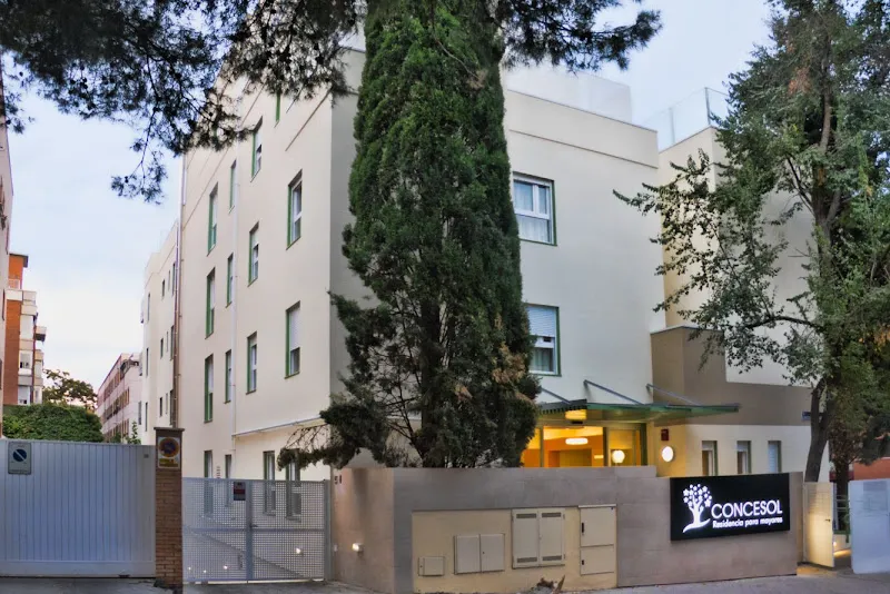 Fachada exterior y entrada iluminada de la residencia mayores concesol entre árboles