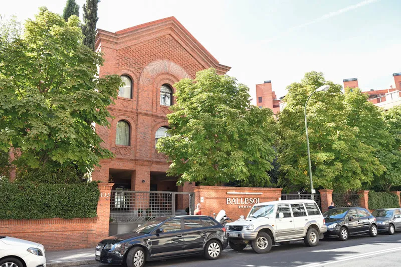 Fachada y entrada arbolada de residencia para mayores ballesol principe de vergara con coches aparcados en la calle