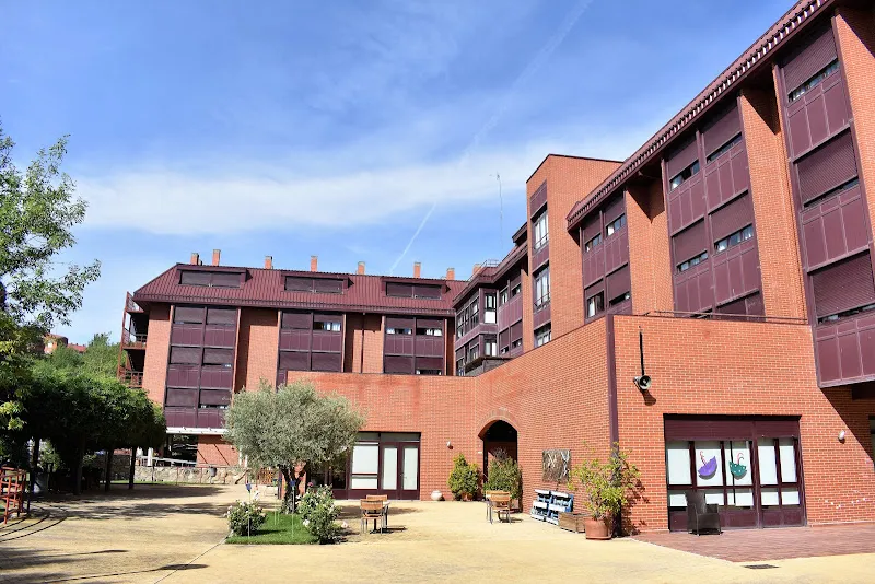 Patio con bancos, árboles y fachada de ladrillo de la residencia para mayores ballesol tres cantos.
