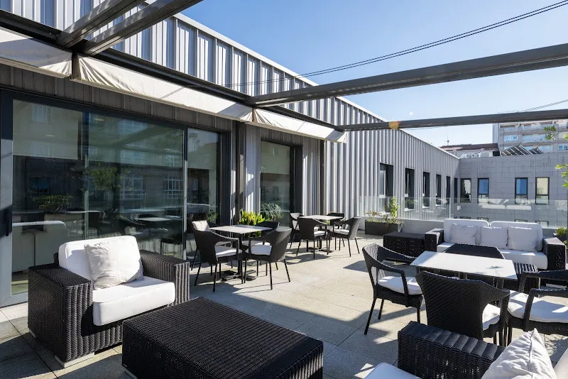 Terraza exterior con muebles de ratán, sofás y mesas en residencia para mayores ballesol vigo