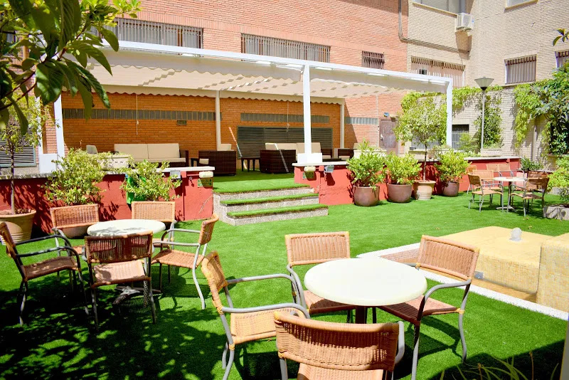 Zona ajardinada con mesas y sillas de la residencia para mayores en madrid ballesol francisco de rojas