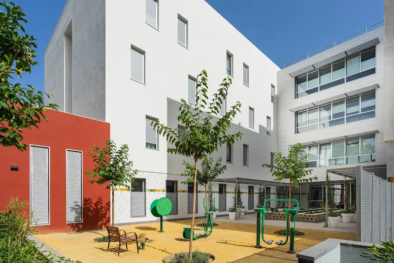 Patio con máquinas de ejercicio al aire libre, bancos y árboles en la residencia para mayores en sevilla ballesol el porvenir.