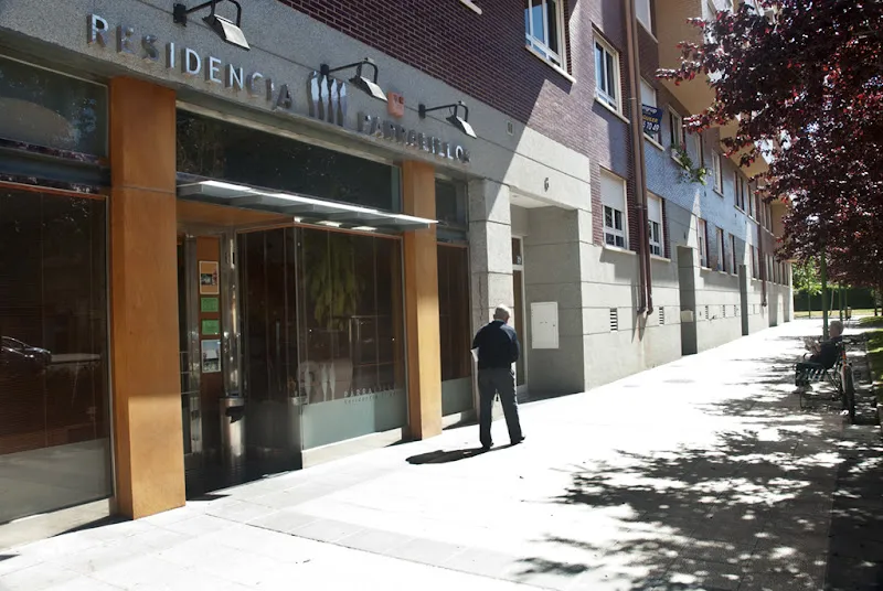 Fachada y entrada de la residencia parralillos de la tercera edad en burgos con una persona caminando frente al acceso