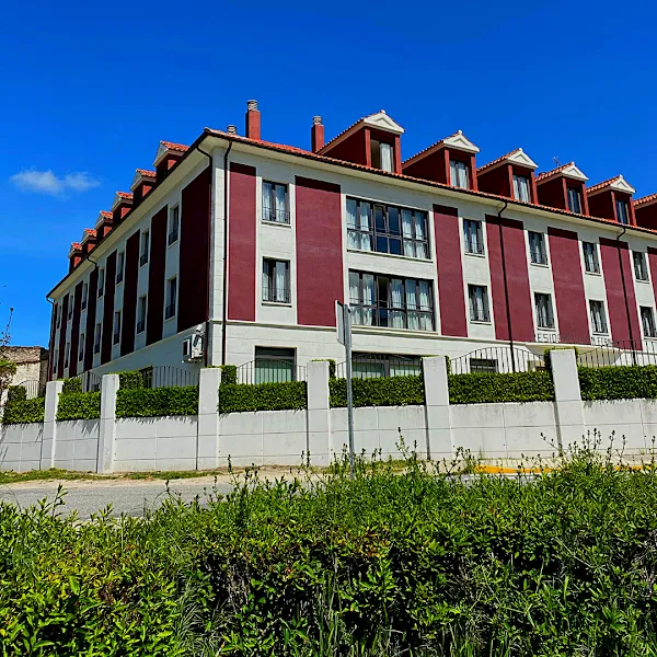 Fachada roja y blanca de la residencia san fernando con ventanas y tejados abuhardillados bajo un cielo azul