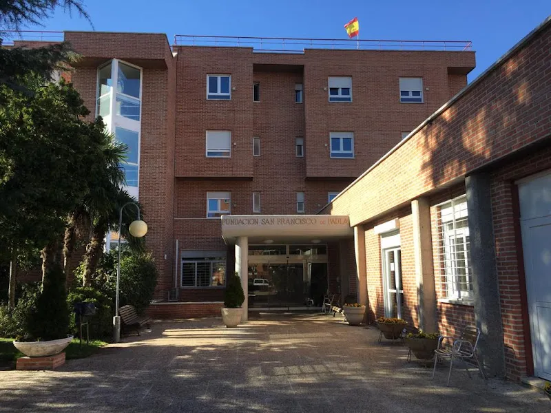 Entrada principal de la residencia san francisco de paula fundacion catalina laboure con fachada de ladrillo, macetas y zona exterior con bancos