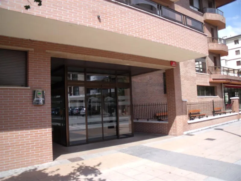 Entrada con puerta de vidrio y fachada de ladrillo de la residencia san martin.