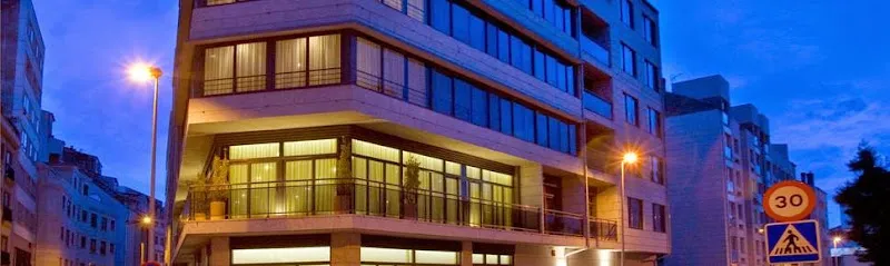 Fachada iluminada de esquina de la residencia serge soremay con grandes ventanales y balcones