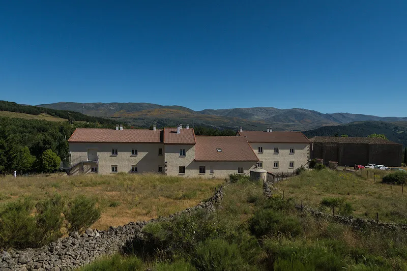 Residencia sergesa virgen del espino en un entorno rural con tejados rojos y montañas de fondo.