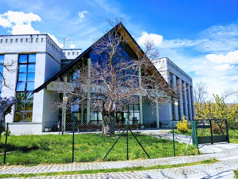 Edificio moderno con gran ventanal, árbol y césped frontal de una residencia tercera idade