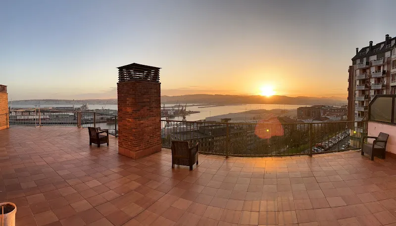 Terraza amplia con baldosas, sillas y vistas al puerto al atardecer en residencia zoragarri