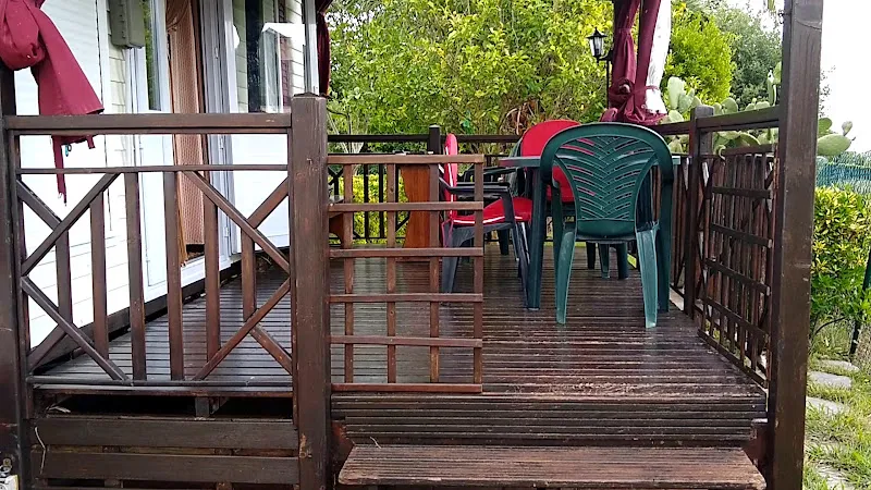 Terraza de madera con sillas y mesa al aire libre — residencias geriatricas de cantabria s l, porche de tarima con barandilla de madera, sillas de plástico y mesa para uso exterior