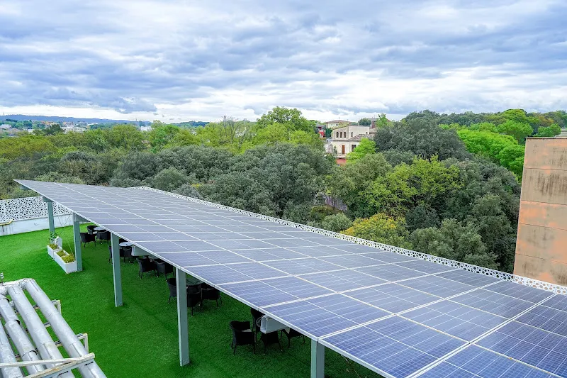 Paneles solares sobre una terraza ajardinada con mesas y vistas arboladas en sanitas residencia de mayores girona