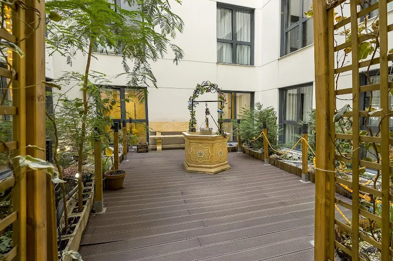 Patio interior con pozo decorativo, celosías y plantas en sanitas residencia de mayores jardines de sabatini